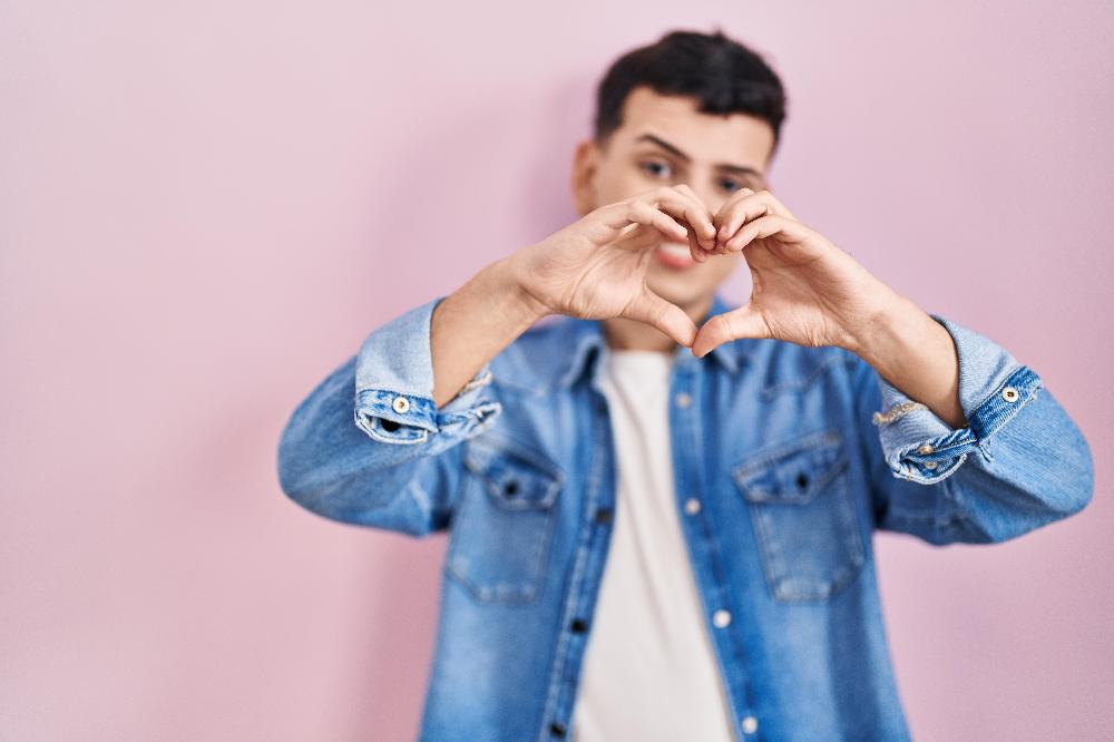 Man making a heart shape with his hands, representing men’s mental health and self-compassion