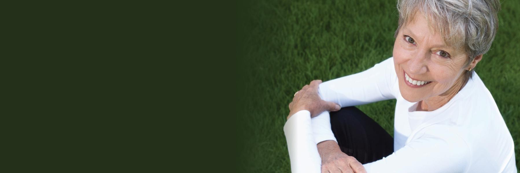 Woman sitting in the grass smiling | Addiction Support Seattle WA