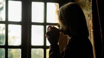 Midlife aged woman looking out window