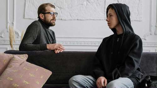 older man and younger man sitting on couch facing towards each other