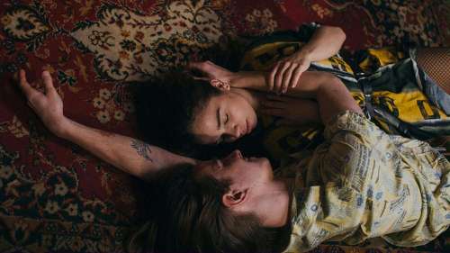 Man and woman couple laying next to each other and touching on red carpet