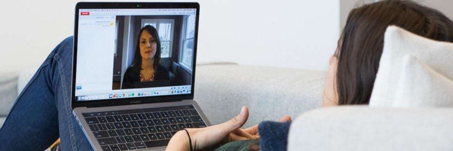 Woman laying on couch doing online therapy in Seattle